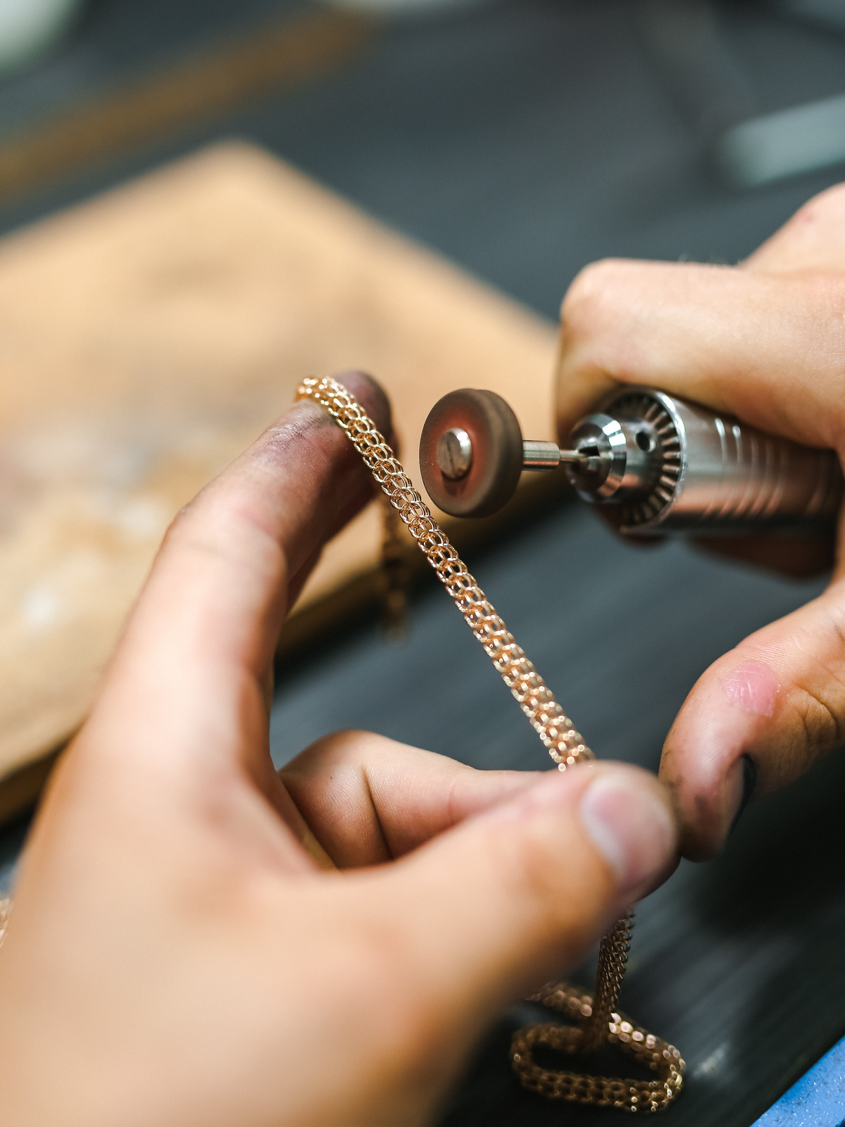 Bijoutier polissant une chaîne en or dans son atelier.