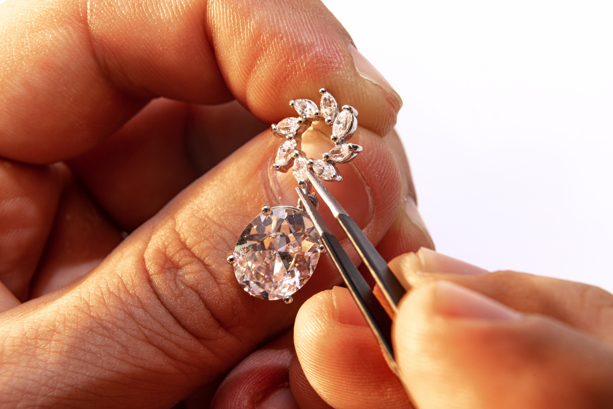 Création d'une boucle d'oreille sertie de pierres précieuses dans un atelier de fabrication de bijoux.