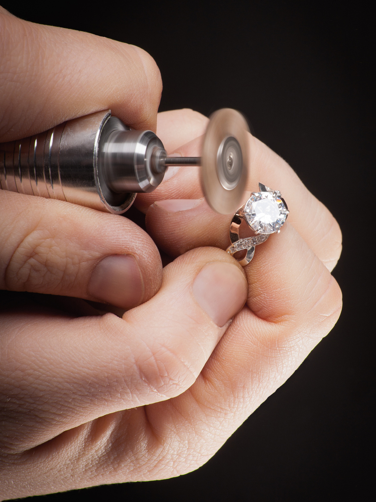 Bijoutier polissant une bague en diamant lors d'une réparation minutieuse.