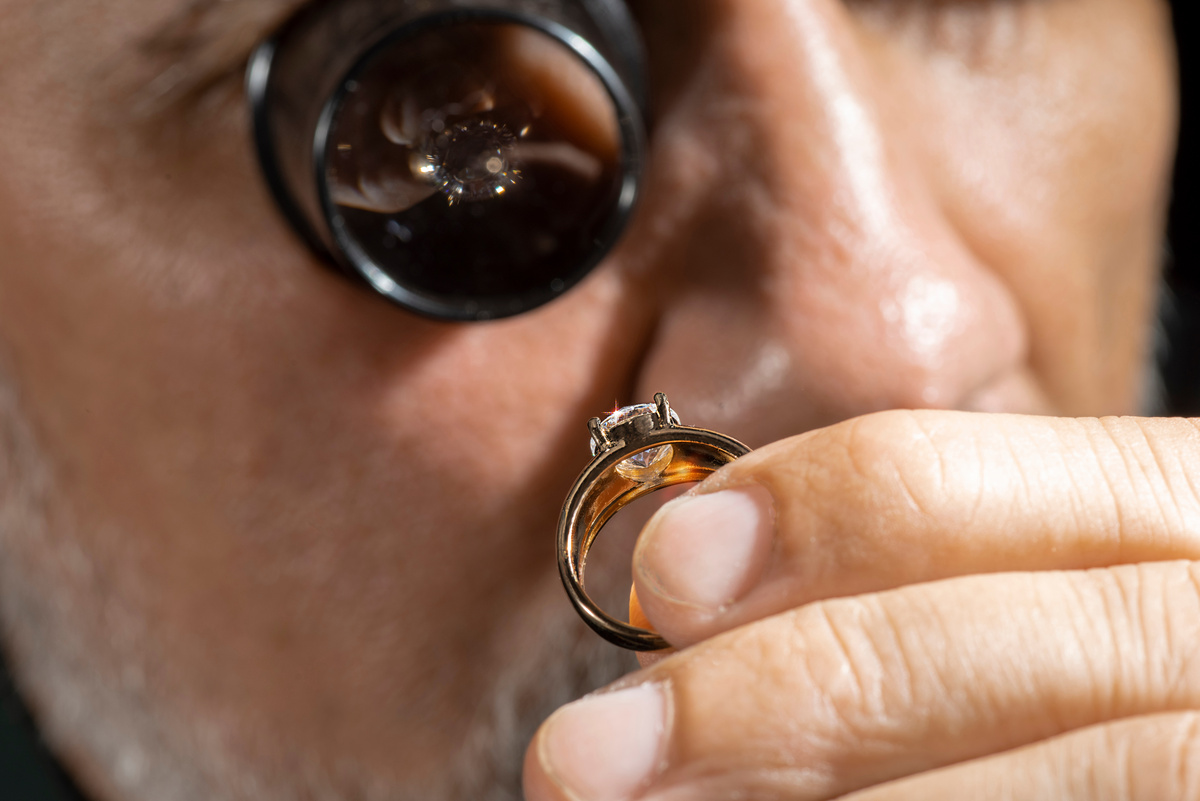 Expert en joaillerie inspectant une bague en diamant pour une réparation précise.